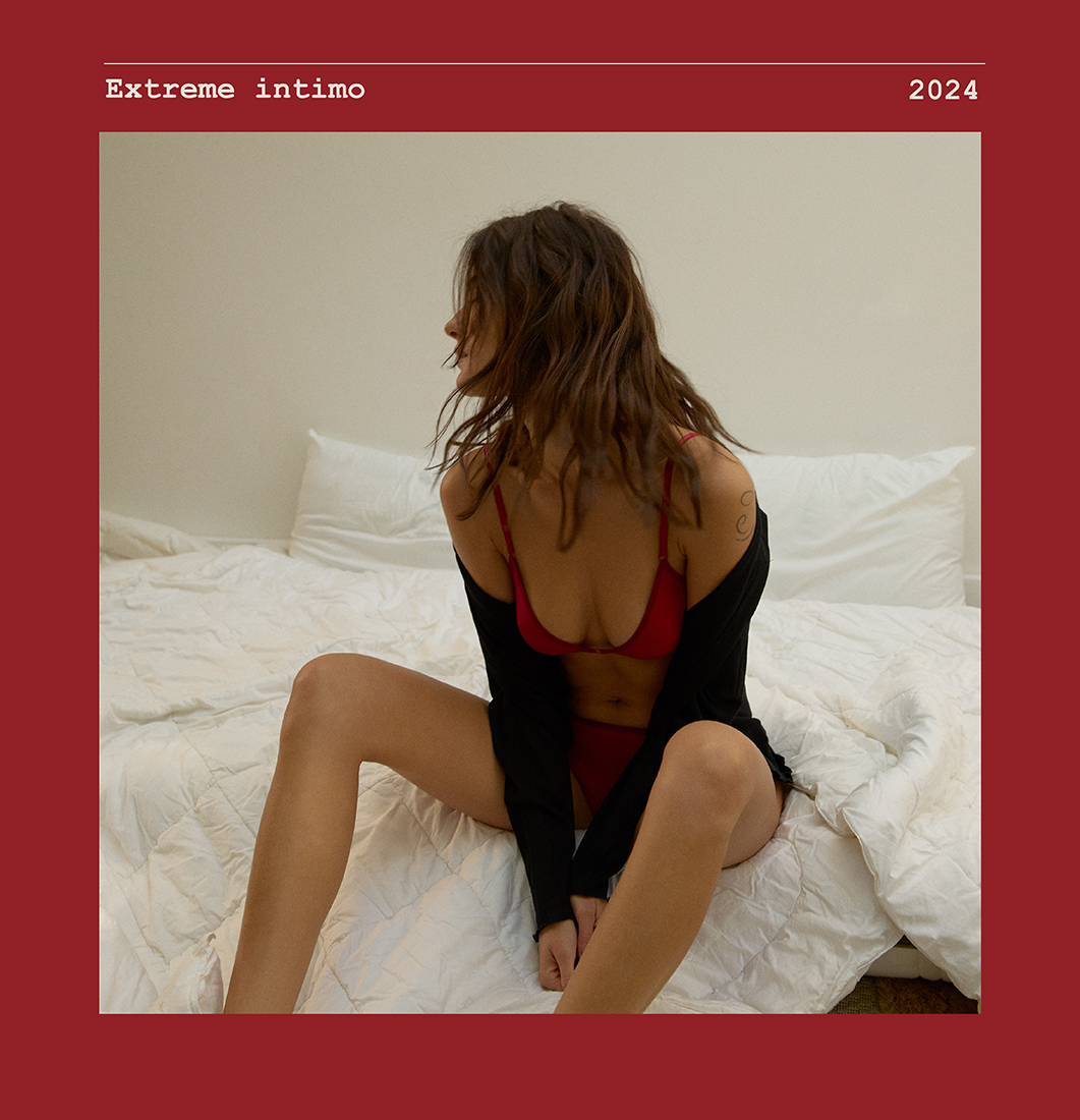 Žena sedi na krevetu u crvenom topu i slipu